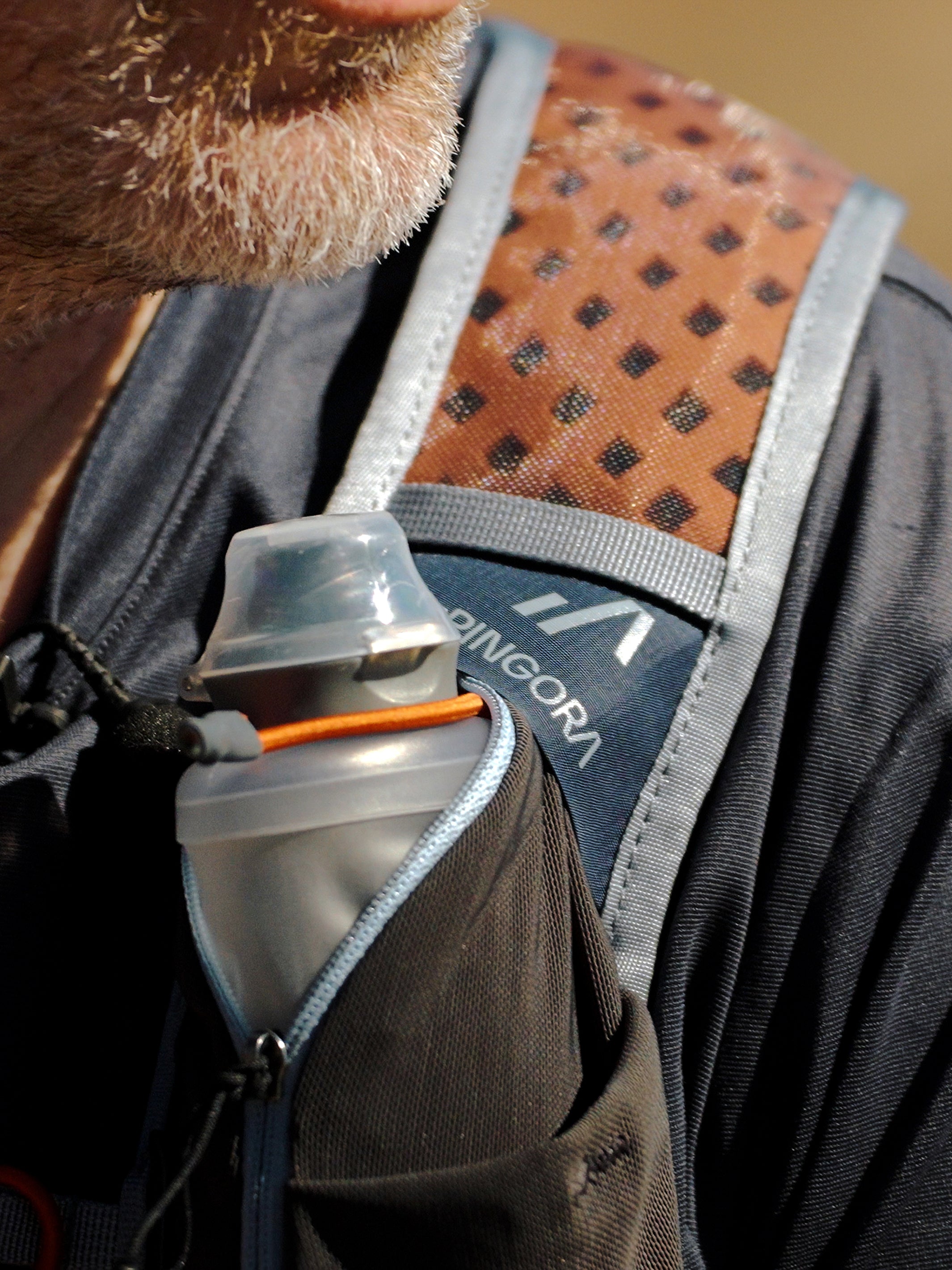 Pingora Lucid 25L hiking backpack showing small water bottle in front harness pocket on live model.