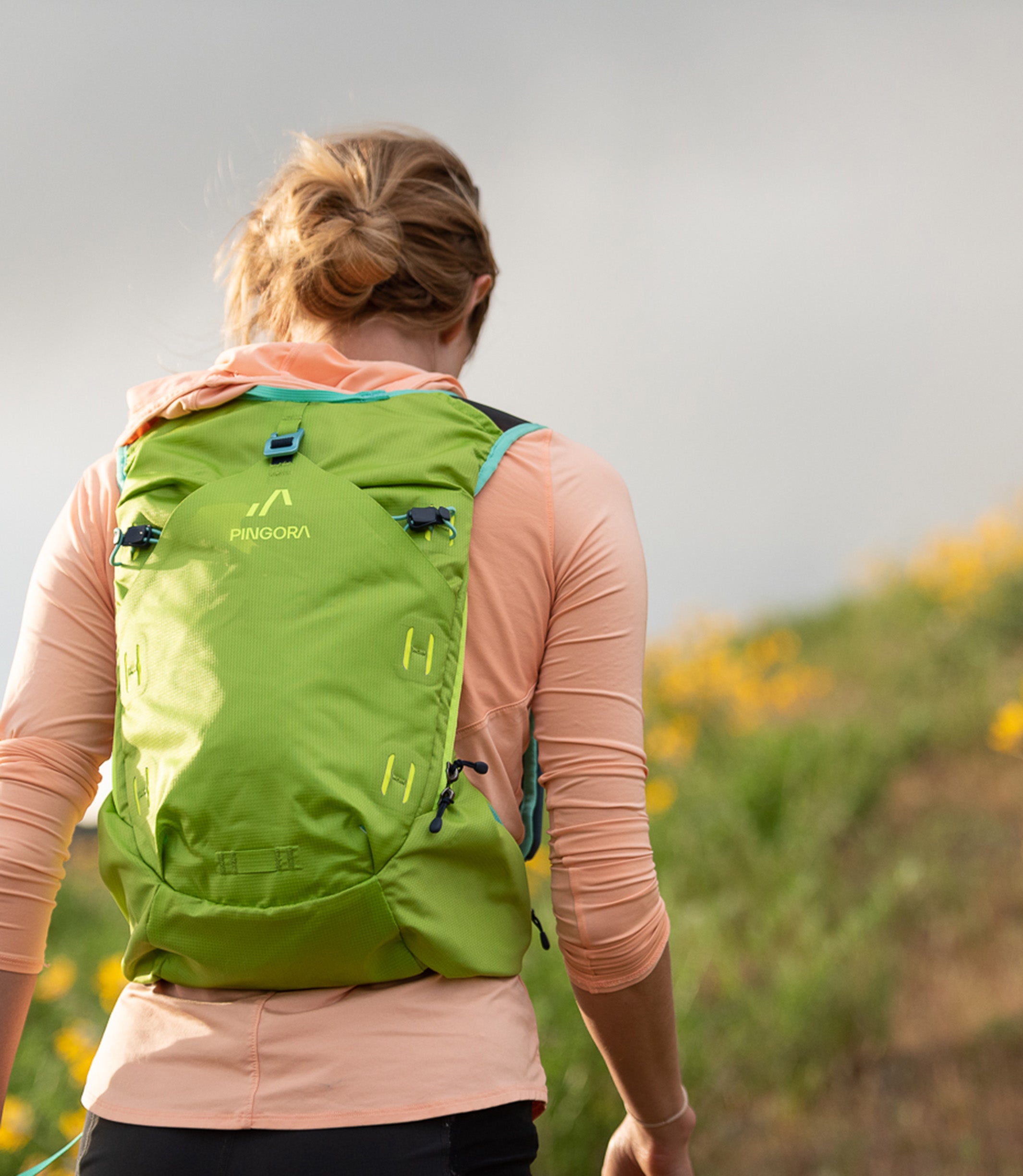 A green Pingora Impulse hydration pack designed for outdoor activities such as hiking and trail running, featuring multiple storage compartments and adjustable straps. Shown on models.