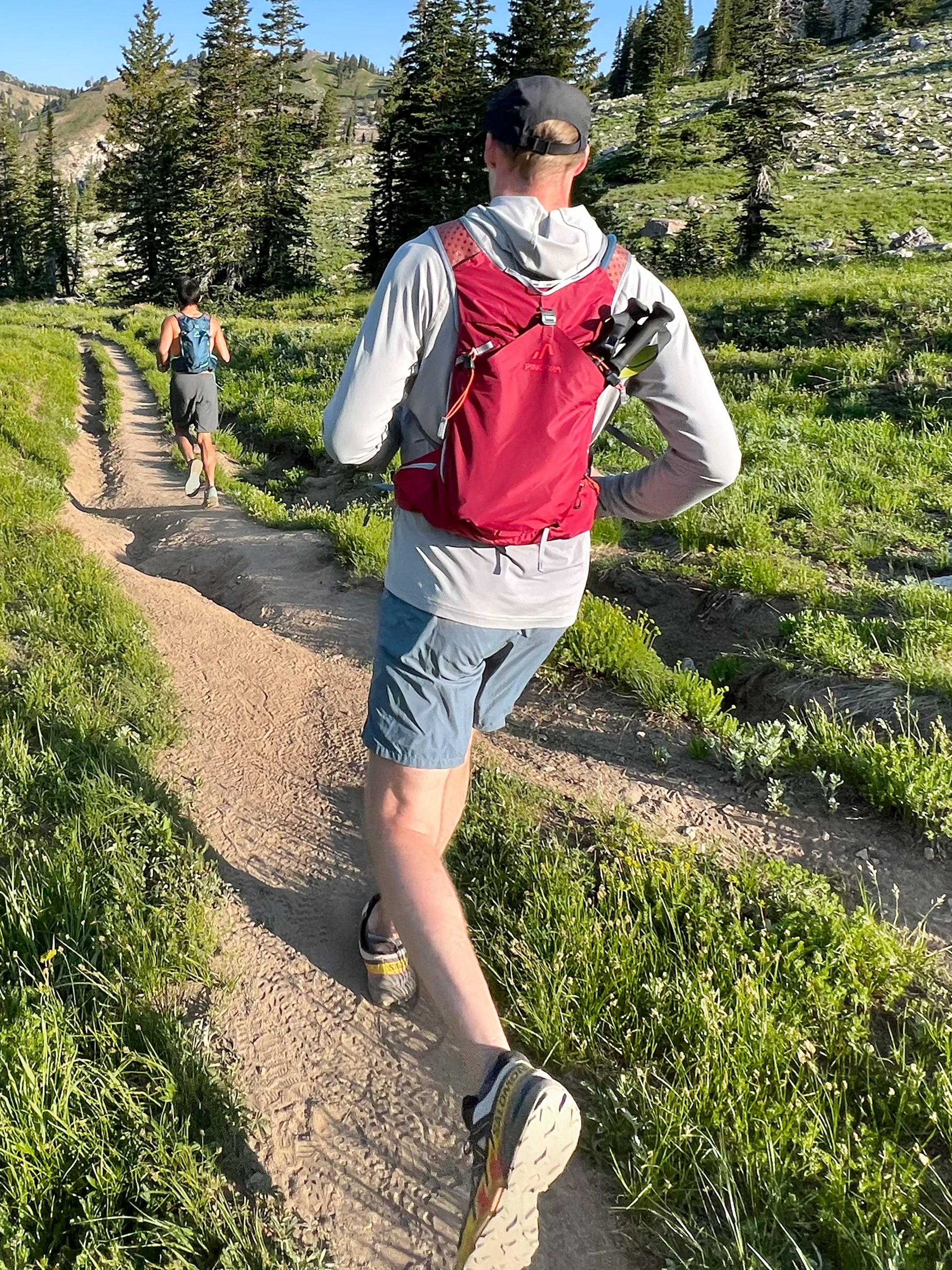 A berry Pingora Impulse hydration pack designed for outdoor activities such as hiking and trail running, featuring multiple storage compartments and adjustable straps. Shown on models.