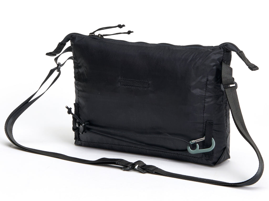 Pingora Satchel in black with black straps and a small blue logo on the front, designed for carrying items while backpacking or traveling.