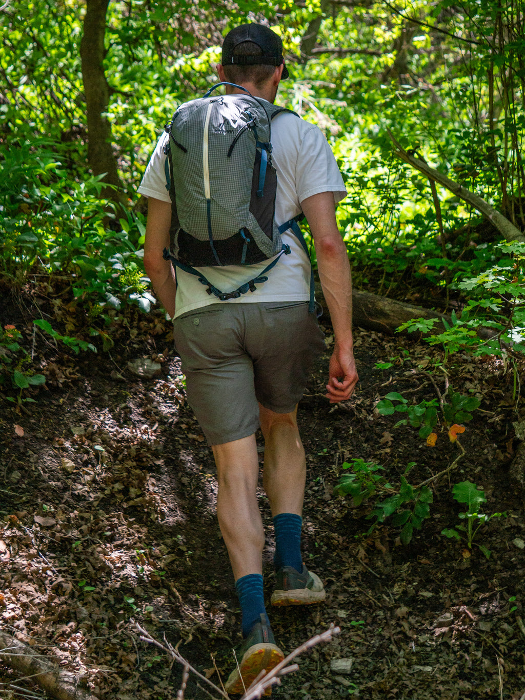 Man hiking on a trail in a forest with a Pingora Lucid 20 hiking backpack