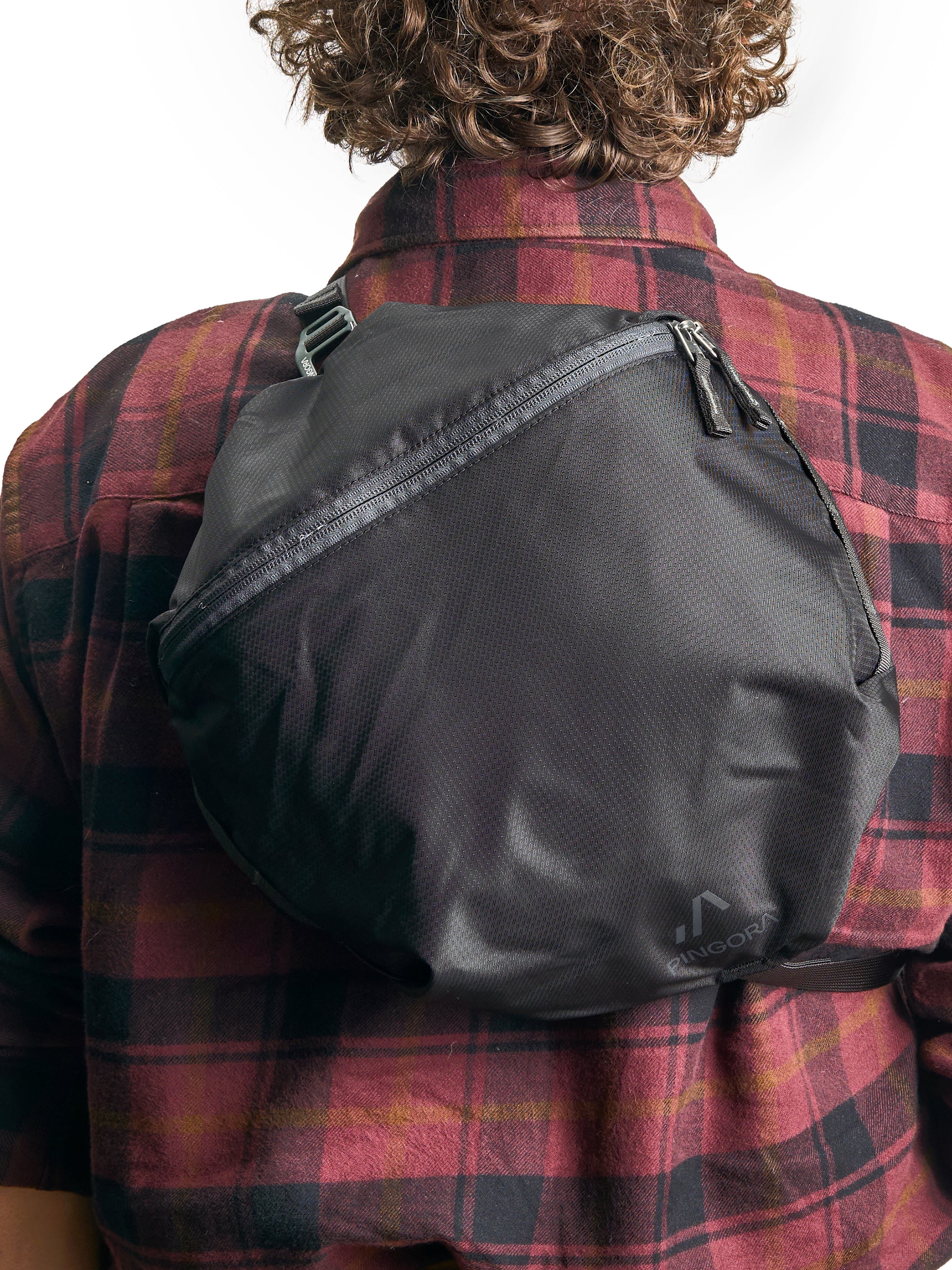 The Pingora Top Pocket for additional backpack storage, branded Pingora, with a zipper closure and a clip attachment. Showing the top pocket used as a small backpack on model.